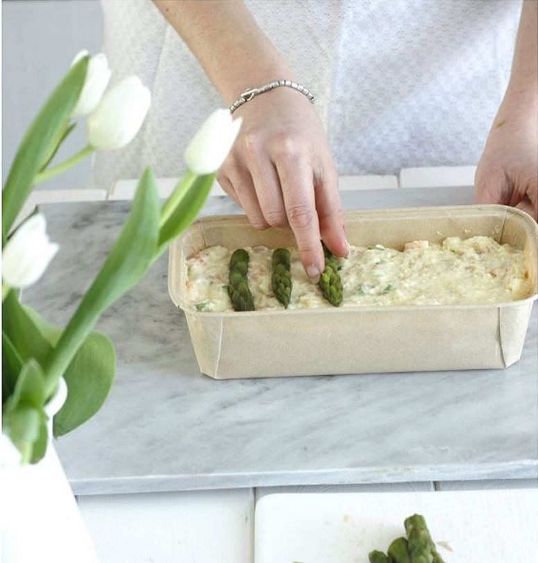mani che mettono le punte di asparagi come decorazione sulla torta prima del forno