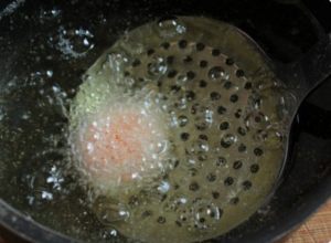 schiumarola che immerge il tuorlo nell'olio bollente
