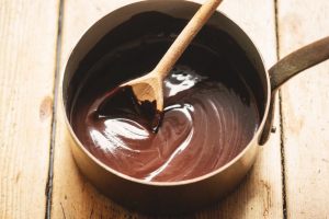 glassa al cioccolato nel pentolino mescolata con un cucchiaio di legno