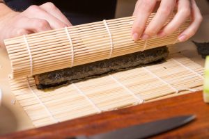 mani che arrotolano il sushi nel bambù
