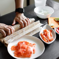 arrotolamento del rotolo di salmone con tappetino da sushi