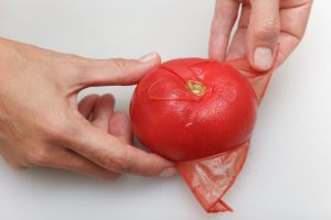 mani che sbucciano un pomodoro