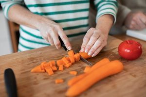mani che tagliano le carote a cubetti